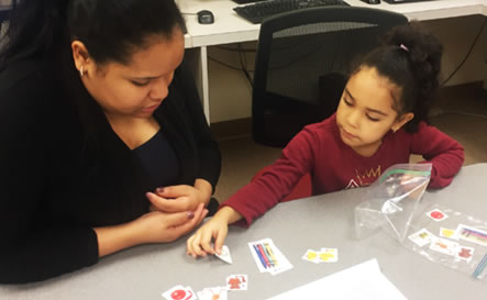 A mother and daughter lay out pieces of paper.