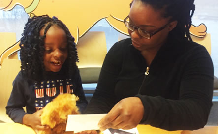 A mother and daughter look at paper.